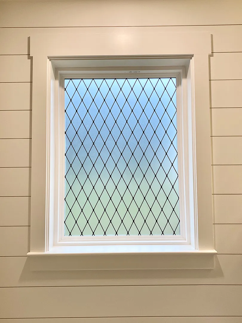 Bathroom window with frosted lattice diamond pattern decorative film in shiplap wall